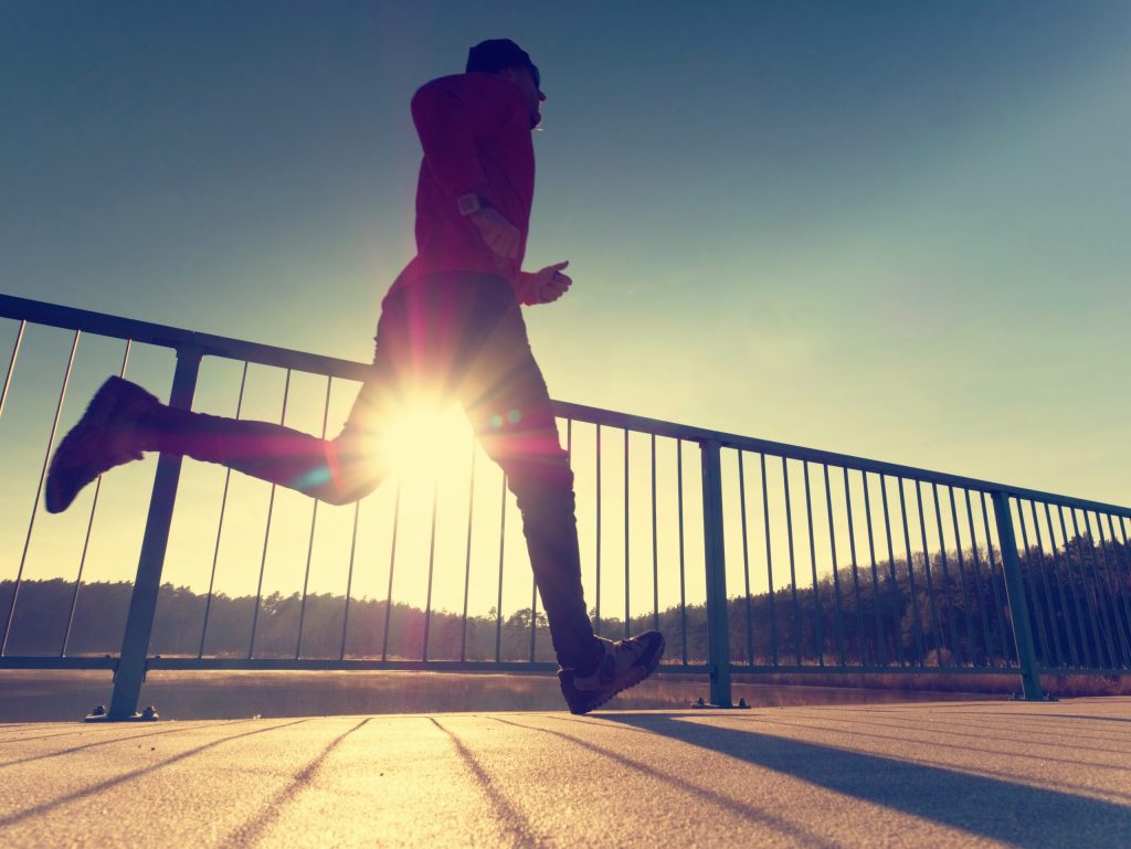 Morning runner in tall black leggings exercising on bridge. Out